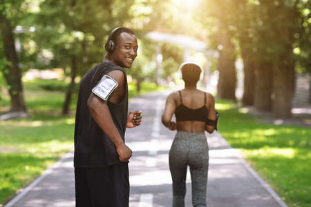 Sport Training. Black Athlete Guy Running With Female Fitness Partner In Park, Enjoying Healthy Lifestyle, Free Spaceの写真素材