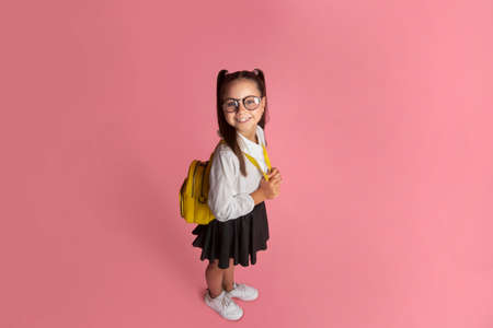 Funny child, early education and school life concept. Happy girl in uniform with backpack looking at camera, top viewの写真素材