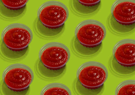 Set of glass bowls with tasty fresh tomato sauce over green background, creative design, repeat pattern, top viewの写真素材