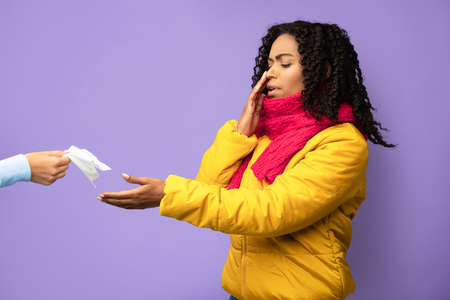 African American Girl Suffering From Nose Bleeding Taking Tissue To Stop Blood Standing On Purple...