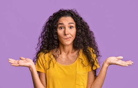 I Dont Know. Doubtful Beautiful Brunette Woman Shrugging Shoulders And Biting Lip Over Purple Studio...