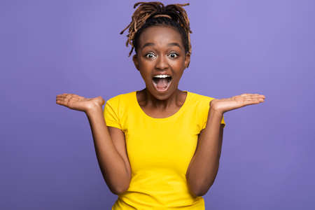 Emotional african american girl expressing amazement over purple studio background