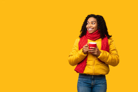 Hot Winter Offer Advertisement. Black Girl Wearing Warm Jacket Holding Coffee Mug Looking Aside At...