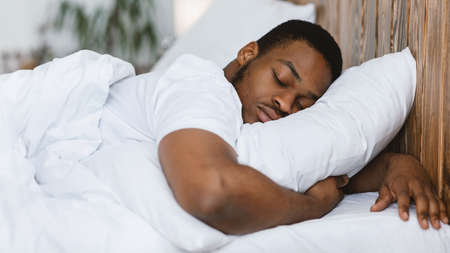 African American Man Sleeping Hugging Pillow Resting Lying With Eyes Closed In Comfortable Bed In...