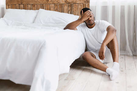 Sick Black Man Having Fever And Headache Touching Forehead Feeling Bad Sitting Near Bed At Home....