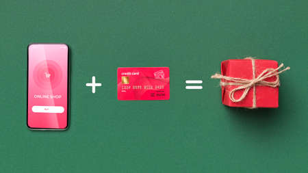 Conceptual collage of smart phone plus credit card equals present box, pink flat lay on green background, mock upの写真素材