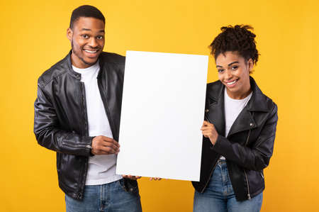 Cheerful African American Couple Showing Blank Poster Board With Copy Space For Text Standing Over...