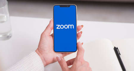 KHARKIV, UKRAINE - JULY 31, 2020: Woman holding cell phone with Zoom Cloud Meetings app logo on screen, bannerのeditorial素材
