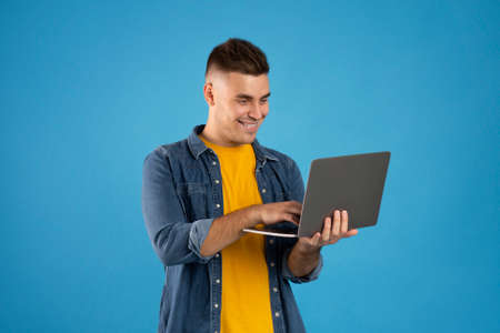 Online travel agency concept. Happy millennial guy with laptop booking tickets, flight or making...