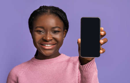 Great App. Mockup image of modern smartphone with black blank screen in hands of beautiful african...