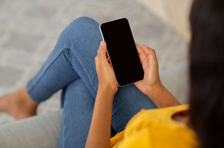 Closeup view of millennial black lady using smartphone with empty screen to work or study online...