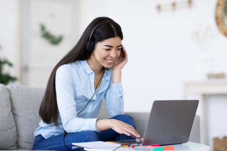 Smiling Young Korean Woman Studying With Laptop And Headset At Home, Enjoying Online Education And...