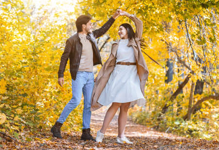 Romantic joyful couple dancing in the middle of autumn forest, enjoying life, copy space