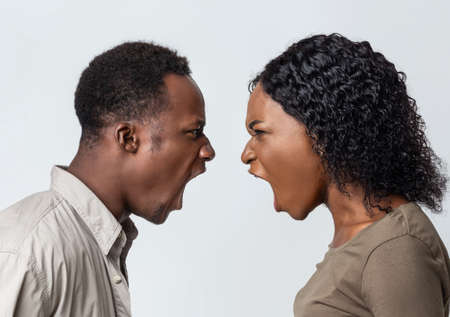 Fight during isolation. Black man and woman shouting at each other over grey studio background. Closeup of african american couple fighting, looking at each other and yelling, profile viewの写真素材