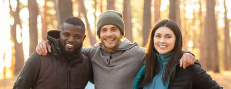 Portrait of three smiling international friends over forest background, panoramaの写真素材