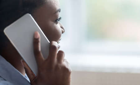 Closeup Portrait Of African American Woman Having Phone Call, Talking On Cellphone And Smiling, Enjoying Pleasant Conversation, Speaking With Somebody, Looking Away, Copy Spaceの写真素材