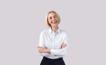 Attractive female businesswoman in formal clothes laughing on light grey studio background. Cheerful...
