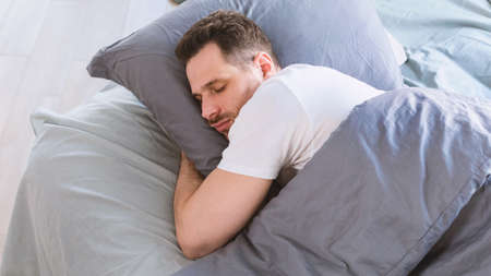 Asleep Man Sleeping Hugging Pillow Lying In Comfortable Bed Resting In Bedroom At Home. Healthy Male Sleep, Recreation And Wellness, Napping Concept. Panoramaの写真素材