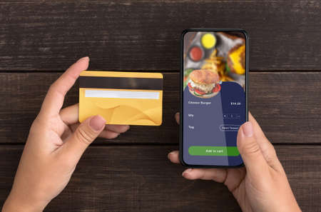Online order at online cafe and payment for food. Woman use credit card and smartphone with...