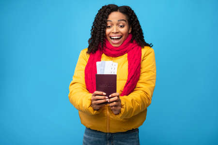 Excited African American Traveler Lady Holding Boarding-Pass Tickets Standing In Studio Over Blue...