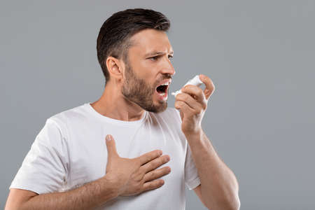 Profile portrait of middle-aged man doing inhalation. Using inhaler treatment. Sick man inhaling...