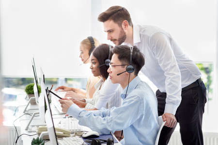 Customer service administrator helping his supervisee to execute clients request at call centre....