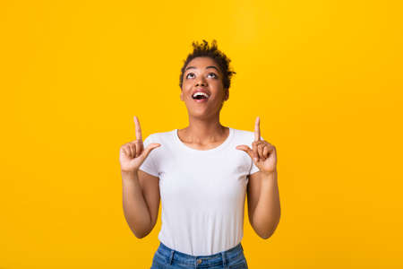 Look There. Portrait of excited african american woman looking and pointing her fingers up at copy...