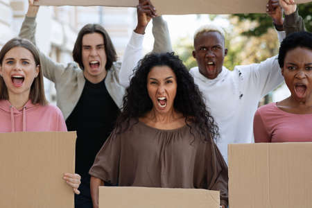 Closeup of desperate strikers with empty placards protesting on the street. International group of...