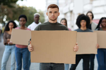 International group of young people strikers with blank placards for tagline standing on the street. Multiracial group of protestors fighting against corruption before President or Parliament electionの写真素材