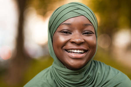 True Happiness. Portrait Of Cheerful Black Muslim Woman In Headscarf Sincerely Laughing While Standing Outdoors On City Street, Positive African Islamic Female Smiling At Camera, Closeup Shotの写真素材