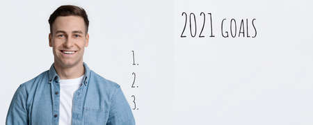 2021 Goals List. Positive Man Setting Goal Checklist For Upcoming New Year Planning Life And Business Posing Smiling To Camera On White Studio Background. Yearly Plans Concept. Panoramaの写真素材