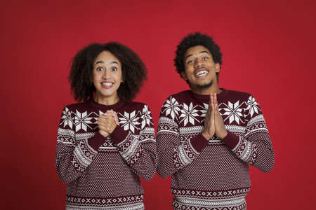 Good luck and great wish for New Year and Christmas. Excited african american couple in sweaters,...