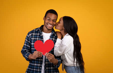 Couple in love, happy emotions and valentine day. Millennial african american woman kissing smiling...