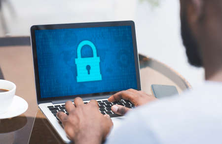 Cyber And Information Or Network Security. Over the shoulder view of black man typing on laptop...
