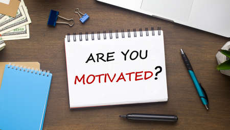 Motivation Concept. Notebook With Text Are You Motivated On Modern Workplace Desk Background With Office Supplies And Money. Business Career Growth. Above View, Flat Layの写真素材