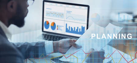 Business Planning. African Businessman Analyzing Annual Financial Reports And Working With Online...