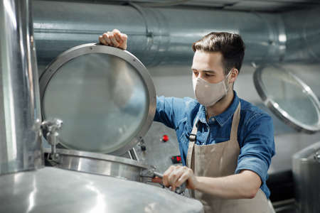Checking of product in manufacturing factory during coronavirus pandemic. Attractive young male...