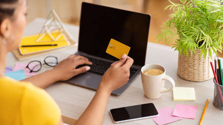 Online Shopping Concept. Over the shoulder view of african american woman holding credit card in...