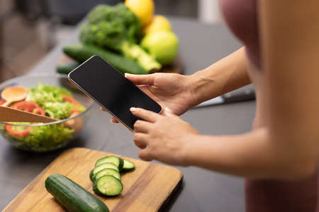 Dieting And Slimming App. Lady Using Phone With Blank Screen Cooking Searching Recipes Online...