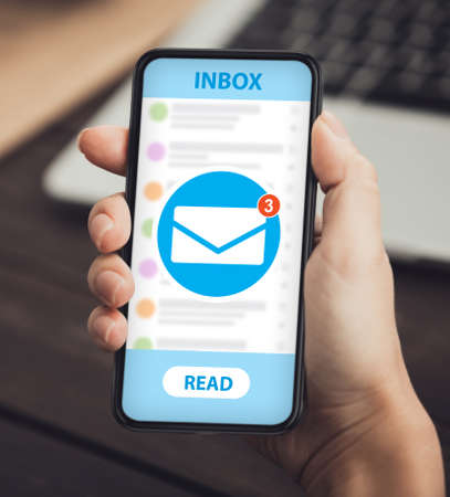 Newsletter and email marketing app for mobile phones. Closeup of female hand holding cellphone with new electronic letter notofication on screen. Woman using mail service for online communicationの写真素材