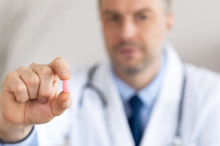 Medicine And Health Care Concept. Doctor holding and showing pill to camera, selective focus on...
