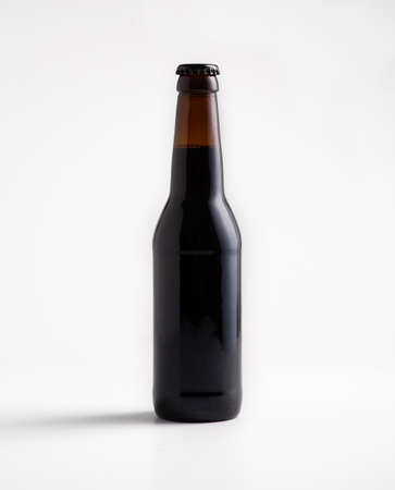 Beer production, pubs and restaurants, advertising great drink offer. Mock up of full craft ale in dark glass bottle without label, isolated on white background, flat lay, free space, studio shotの写真素材