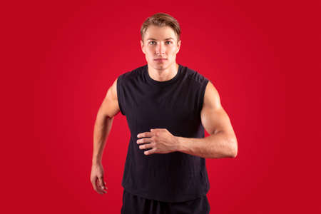 Sports and healthy lifestyle concept. Determined millennial athlete running on red studio...