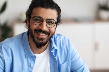 Closeup Portrait Of Positive Indian Guy With Dental Braces And Eyeglasses Smiling At Camera, Handsome Bearded Millennial Man With Brackets On Teeth Posing Indoors, Selective Focus With Copy Spaceの写真素材