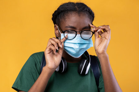 Dont Touch Your Face. Black Female Student Wearing Medical Mask And Scratching Eye Standing Over...