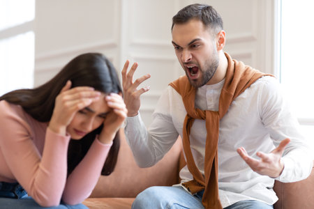 Aggressive Arab Husband Shouting At Unhappy Victimized Wife Sitting On Couch At Home. Family...