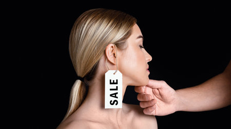 Weaker sex and protection of rights. Male hand touches to face of disappointed woman with label on ear with inscription sale, panorama, copy space, studio shotの写真素材