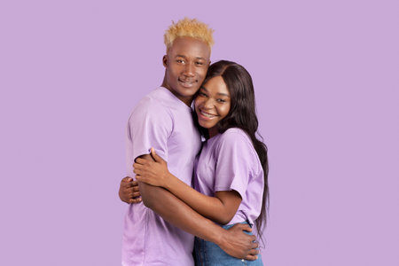 Beautiful black couple feeling in love, embracing and feeling happy over violet studio background....