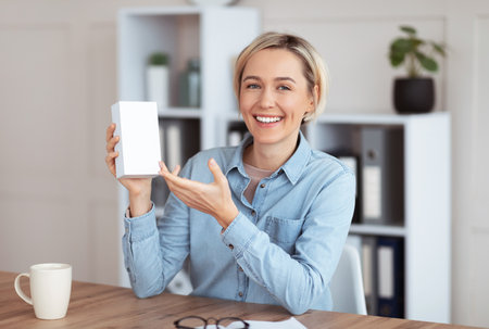 Young female blogger recording video review of new modern device, demonstrating tech product at home, mockup for design. Positive millennial vlogger promoting new model of gadgetの写真素材