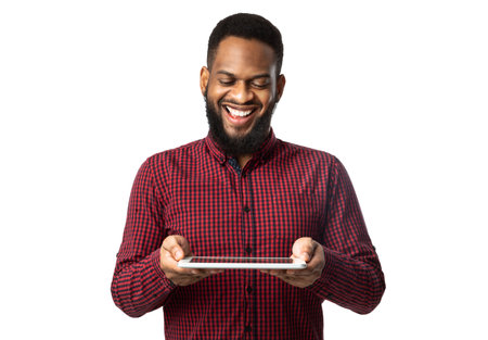 Cheerful African American Man Holding Digital Tablet Standing On White Background. Bearded Black Guy Playing Computer Game Online In Studio. Website, Internet Service And New Application Advertの写真素材